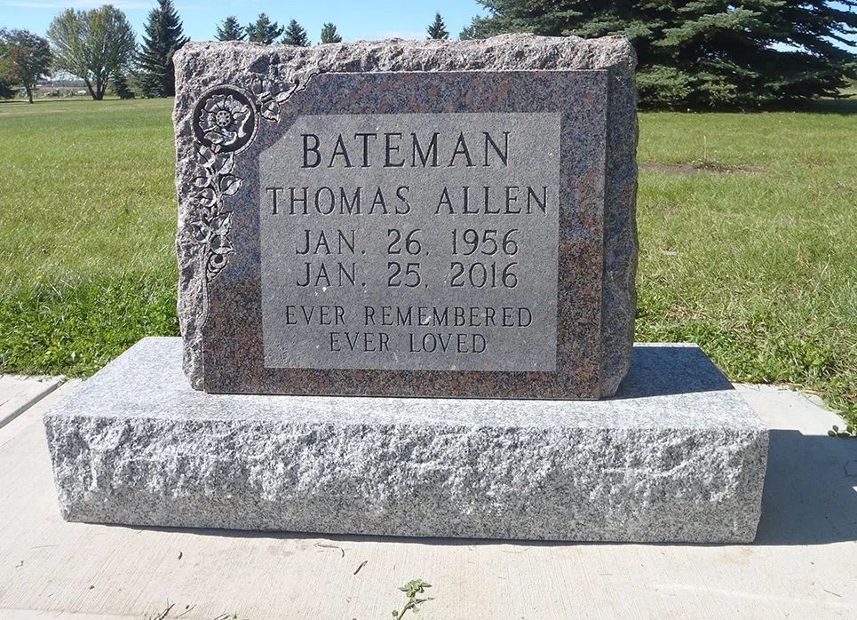 Granite memorial bench and headstone in a grassy cemetery with engraved names and dates.