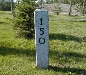 Gray stone marker with the number 150 standing in a grassy park