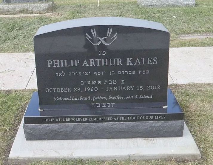 Black gravestone with white lettering in a grassy cemetery, marked for Philip Arthur Kates.