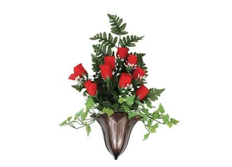 Red roses and green foliage in a decorative wall vase with a bronze finish