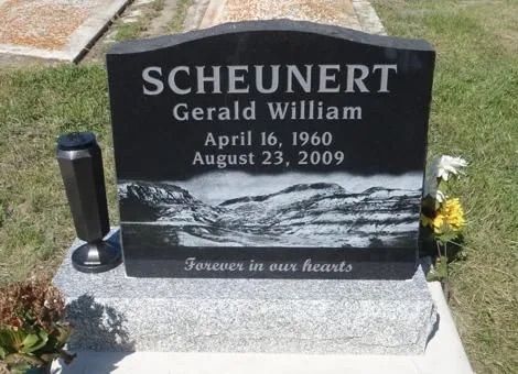 Black granite gravestone with flowers, reading “SCHEUNERT Gerald William” and dates April 16, 1960–August 23, 2009.