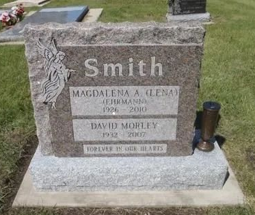 Smith family gravestone in a cemetery with flowers and a small lantern beside it.