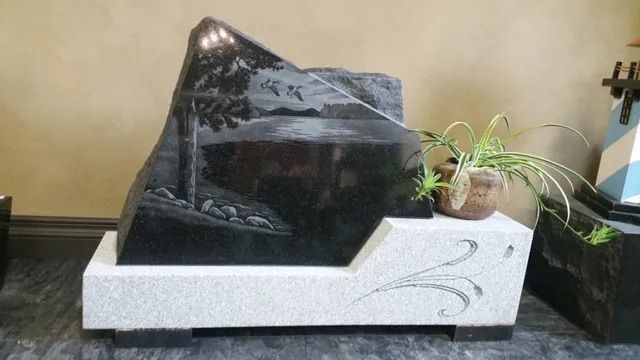 Indoor decorative tabletop fountain with black rock and white base, beside a small potted plant
