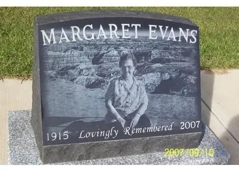 Gray memorial headstone for Margaret Evans, with dates 1915 and 2007, set in grass.