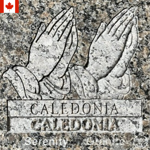 Stone plaque with praying hands and the words “CALEDONIA” and “CALEDONIA,” with a small Canadian flag icon