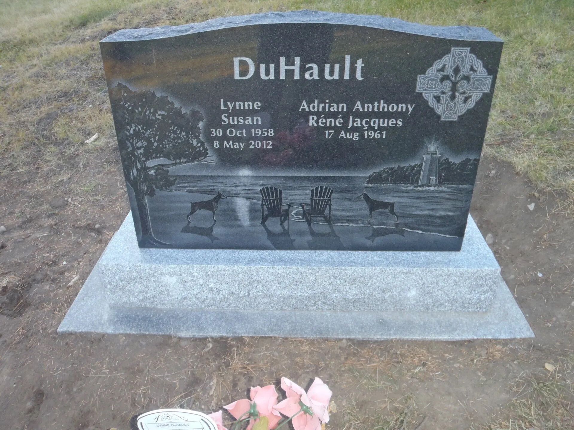 Black granite gravestone with “DuHaul” engraved, set on a concrete base with pink flowers in front.