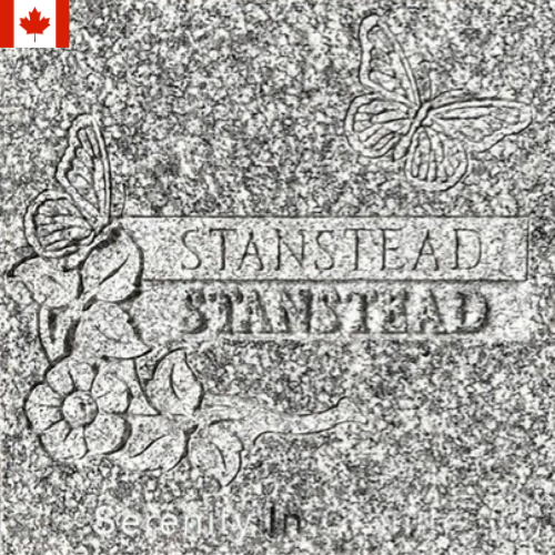 Gray stamped plaque with butterfly and floral designs, labeled “STANSTEAD” twice, with a small Canada flag icon.