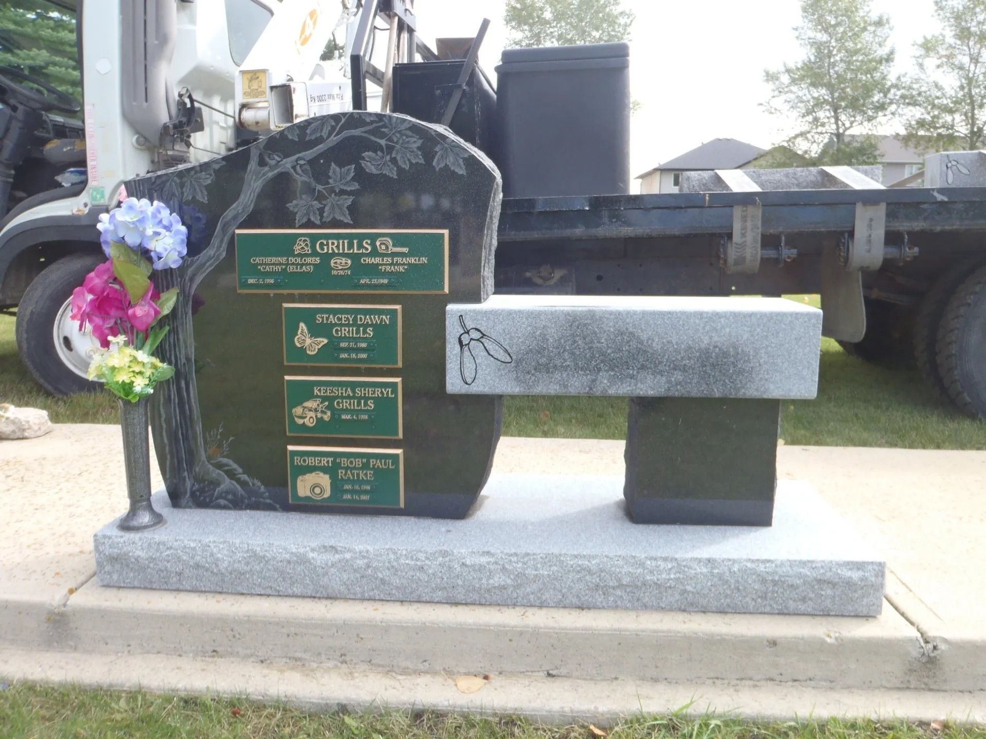 Black granite funeral monument with commemorative plaques and decorative flowers