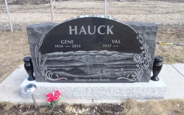 Black granite memorial headstone with silver dove engraving and flowers at the base