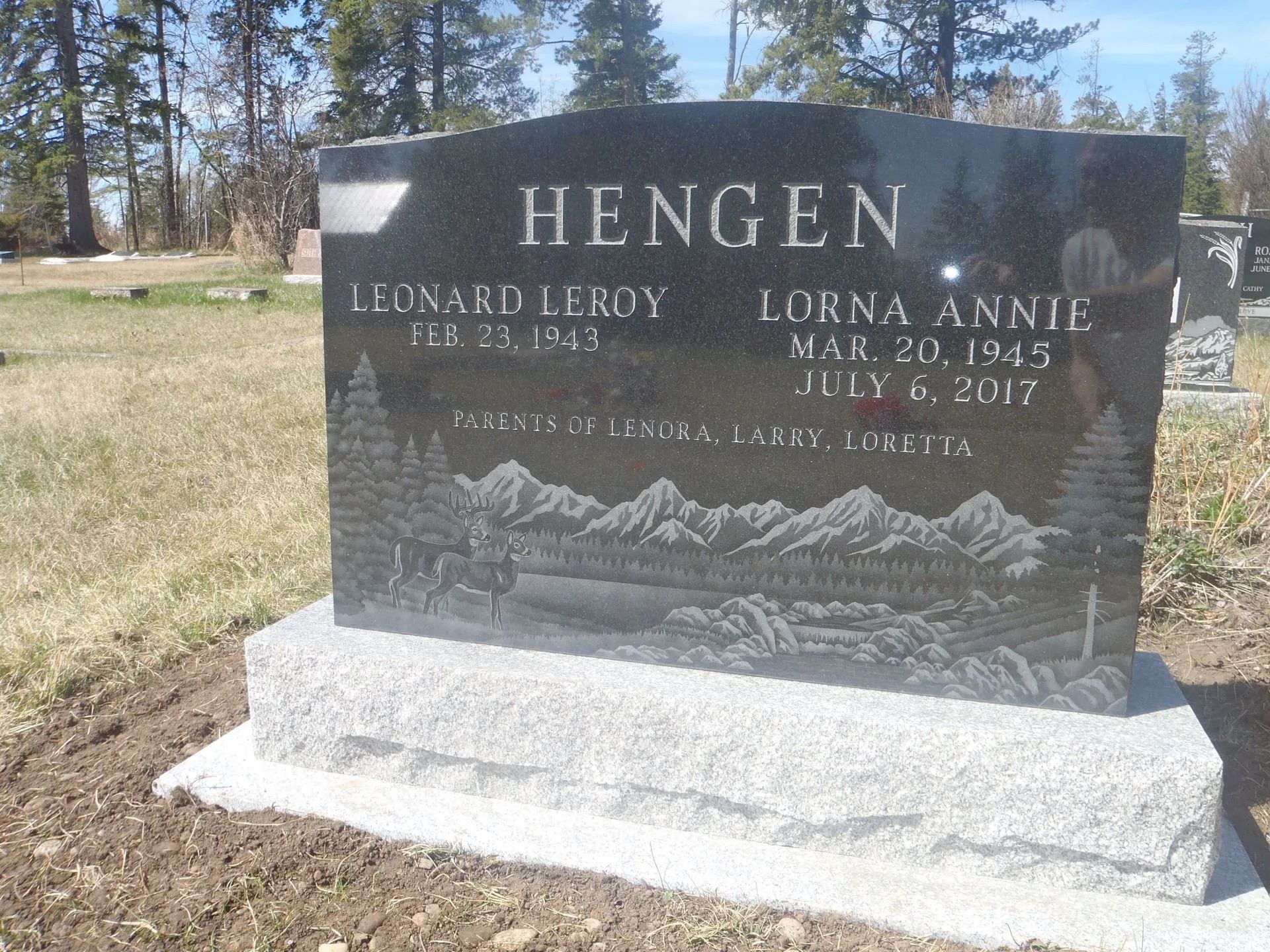 Black granite memorial headstone with “Hengen” engraved, set on a gray base in a grassy cemetery.