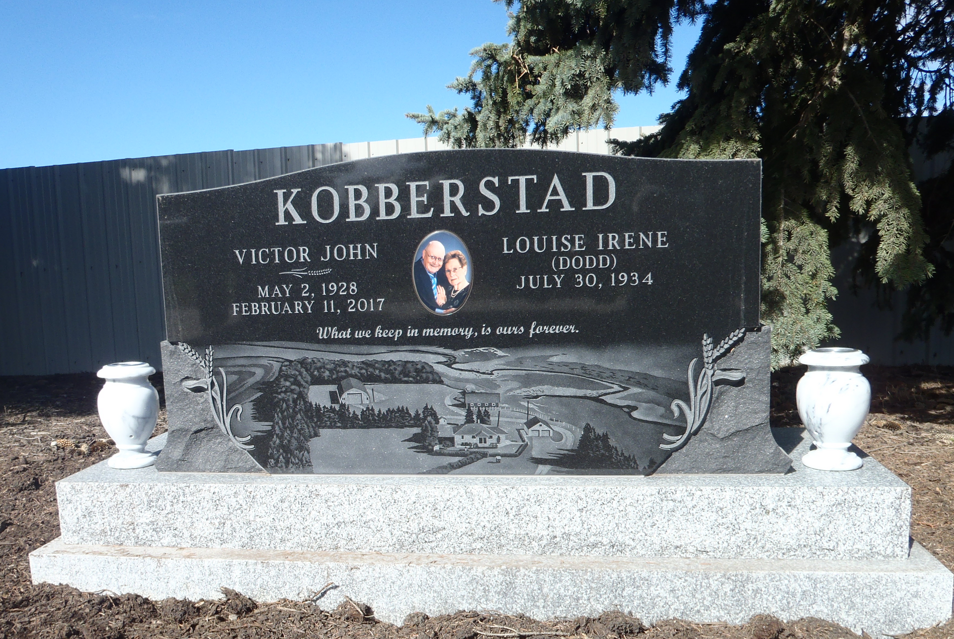 Kobberstad gravestone with engraved names and white vases in a cemetery