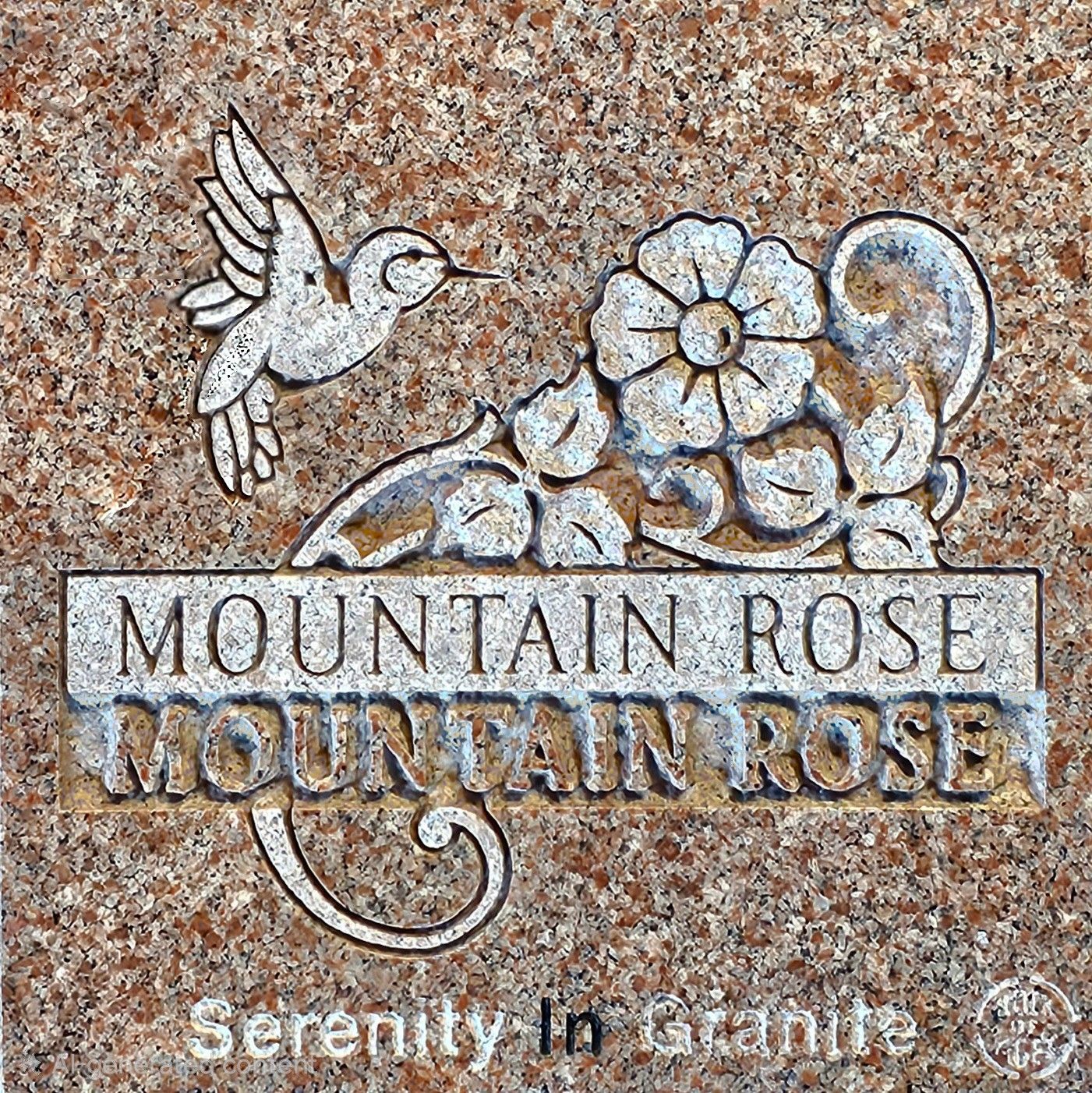 Gray granite memorial stone with an engraved hummingbird and floral design.