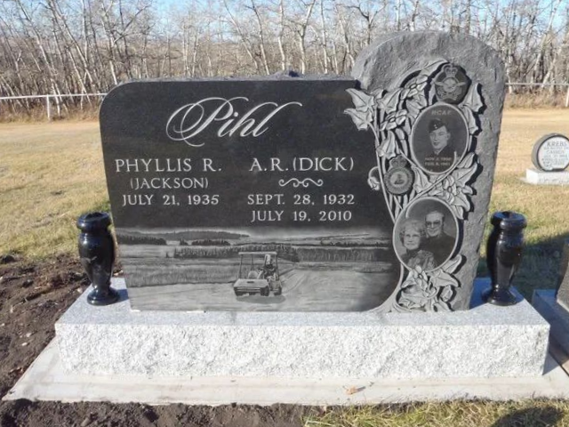 Black granite gravestone with carved rose on a concrete base in a cemetery.