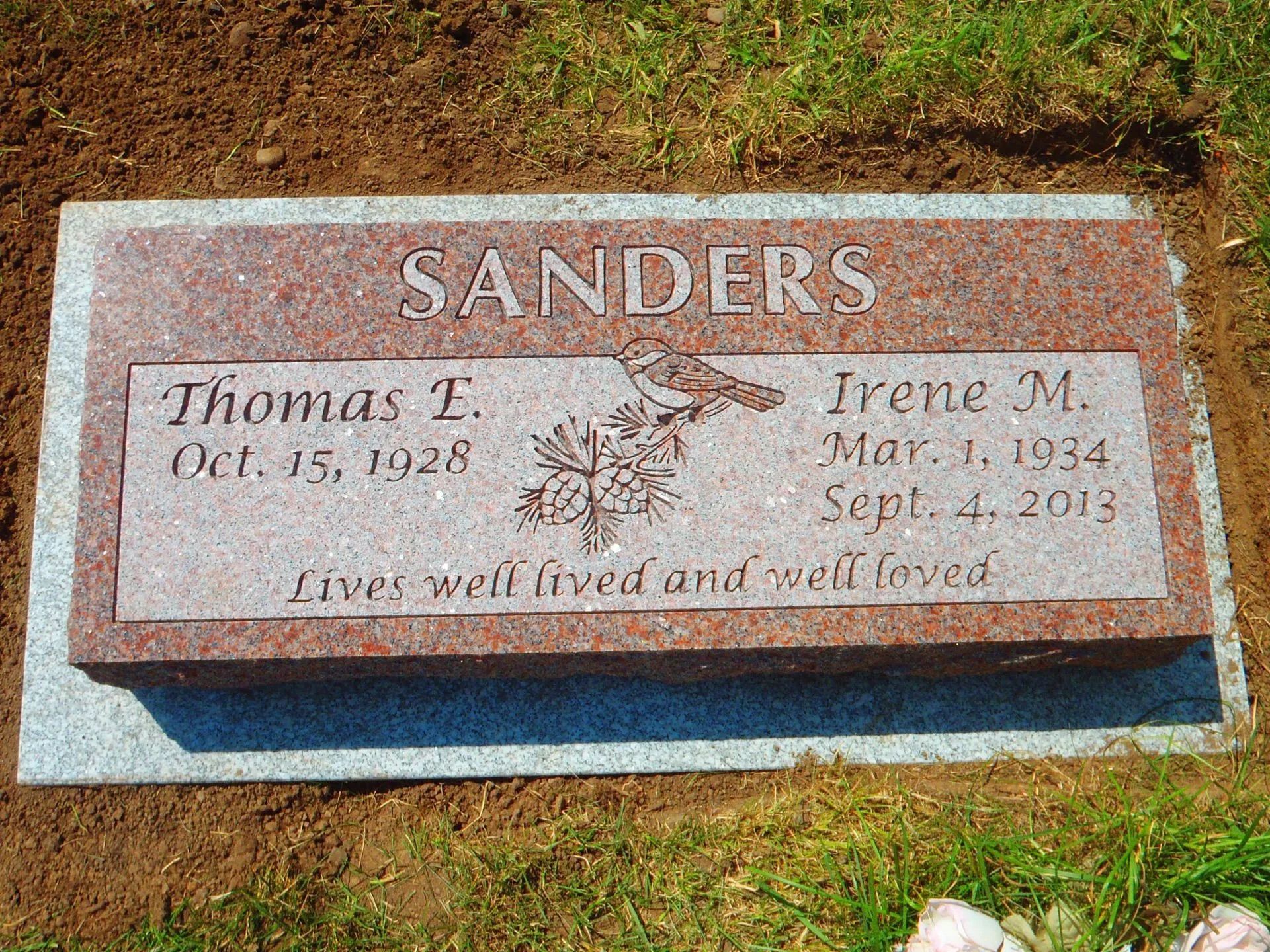 Red granite headstone bearing names Thomas E. and Irene M. Sanders with birth and death dates