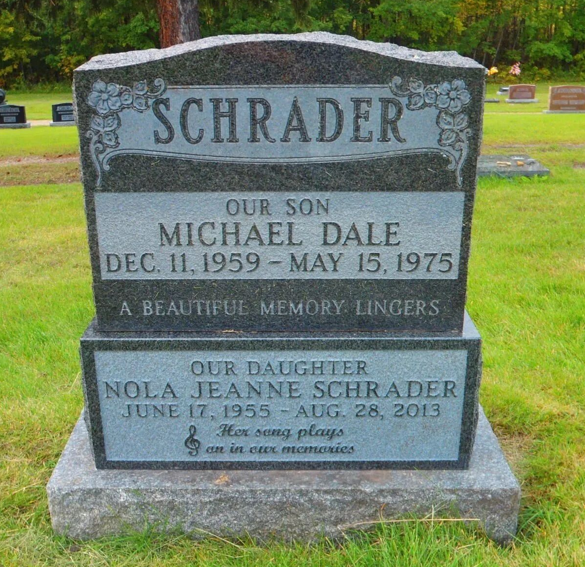 Schrader family gravestone in a cemetery, gray stone with engraved names and dates.