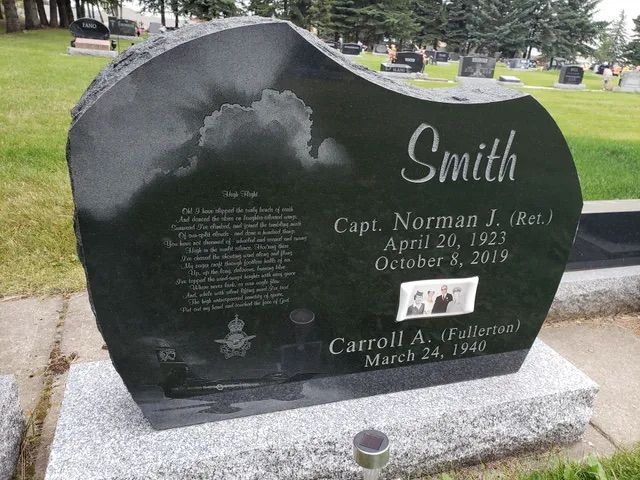Black granite gravestone in a cemetery with the surname Smith and engraved names and dates.