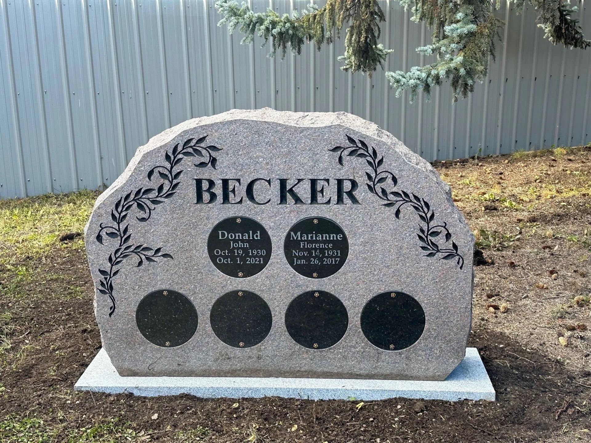Gray headstone engraved with BECKER name, two circular plaques containing names and dates, and four circular plaques