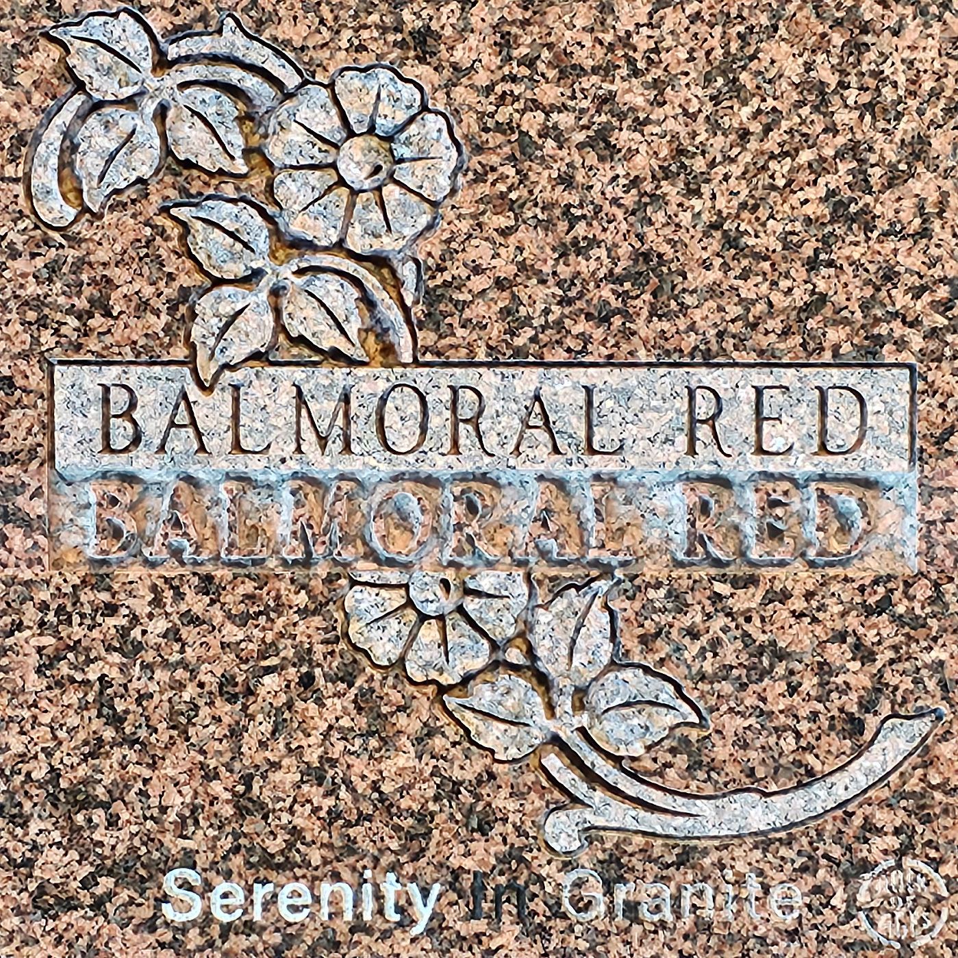 Balmoral Red granite sample with floral engraving and “Serenity in Granite” text on speckled pink stone