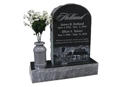 Black granite memorial headstone with carved portraits and flowers beside it