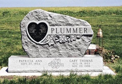 Gray headstone with engraved heart and PLUMMER, set in a grassy cemetery with a small lantern.