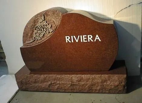 Brown stone monument with engraved floral design and the word “RIVIERA” on a base