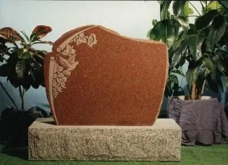 Decorative orange stone plaque on a stone base, flanked by potted plants indoors