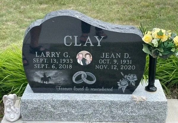 Black gravestone for Larry C. Clay and Jean D. Clay with flower vase and engraved dates