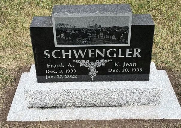 Black granite gravestone with the name Schwenlger and a photo plaque on a white base.