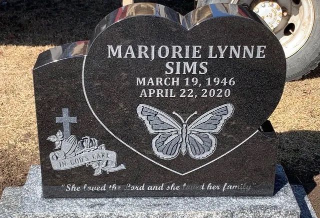 Gravestone for Marjorie Lynne Sims with butterfly engraving and cross in a cemetery.