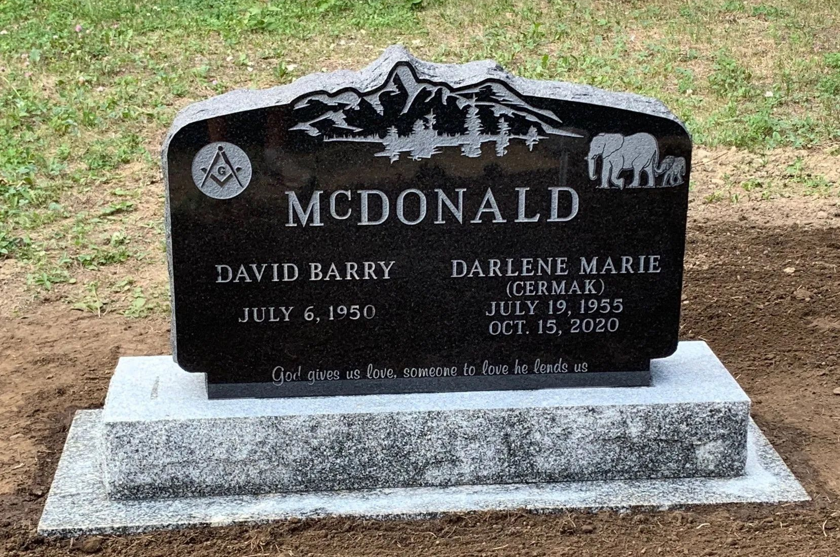 McDald family gravestone with engraved names and mountain scene in a cemetery