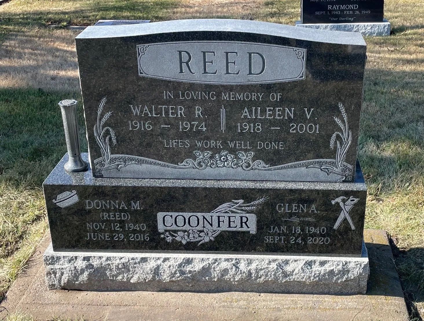 Engraved granite memorial headstone for Reed and Coomer in a grassy cemetery.