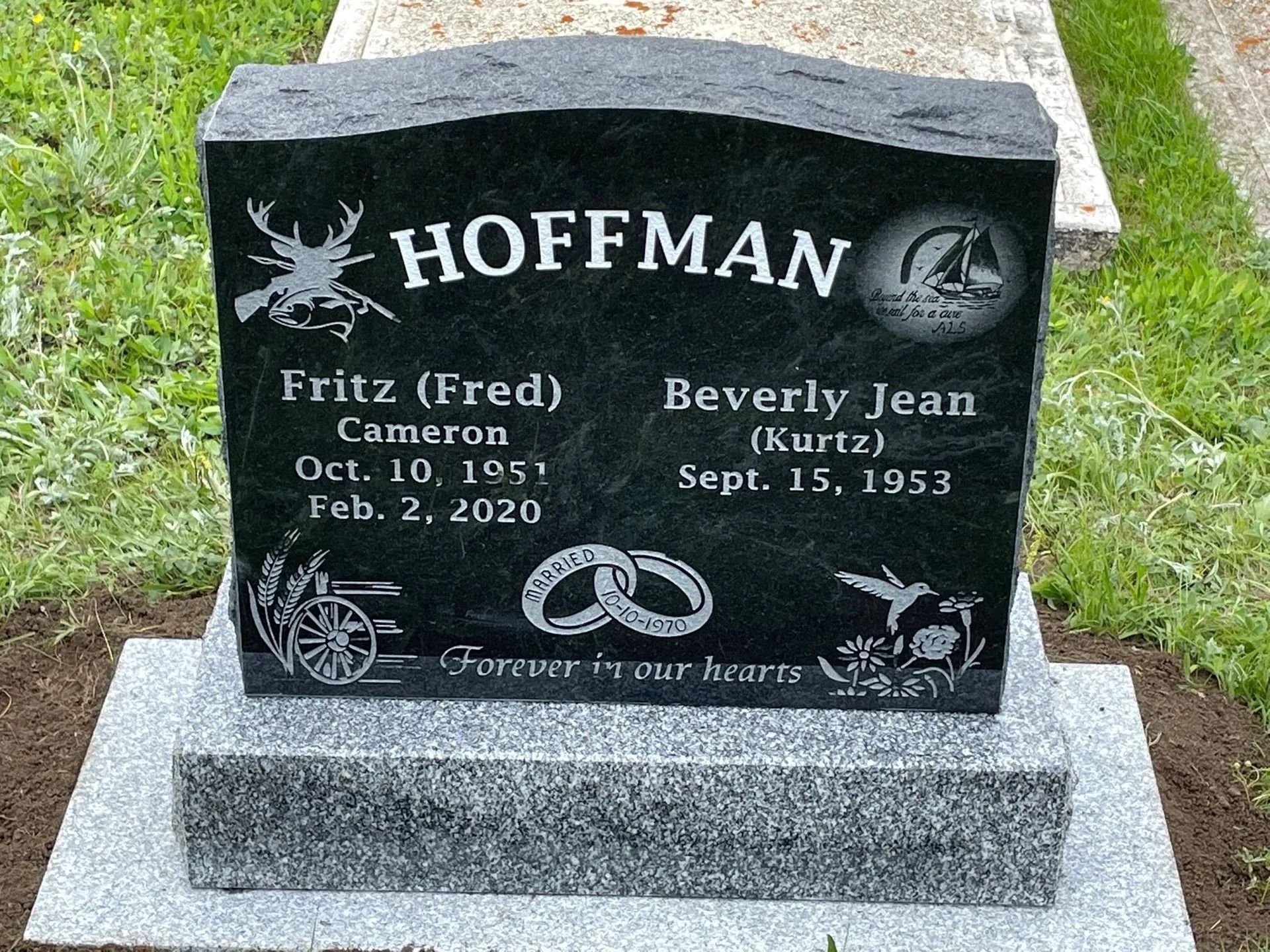 Black Hoffman gravestone with engraved names and dates in a cemetery