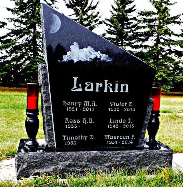 Larkin family gravestone with engraved names, moon and clouds, beside a red candle in a cemetery