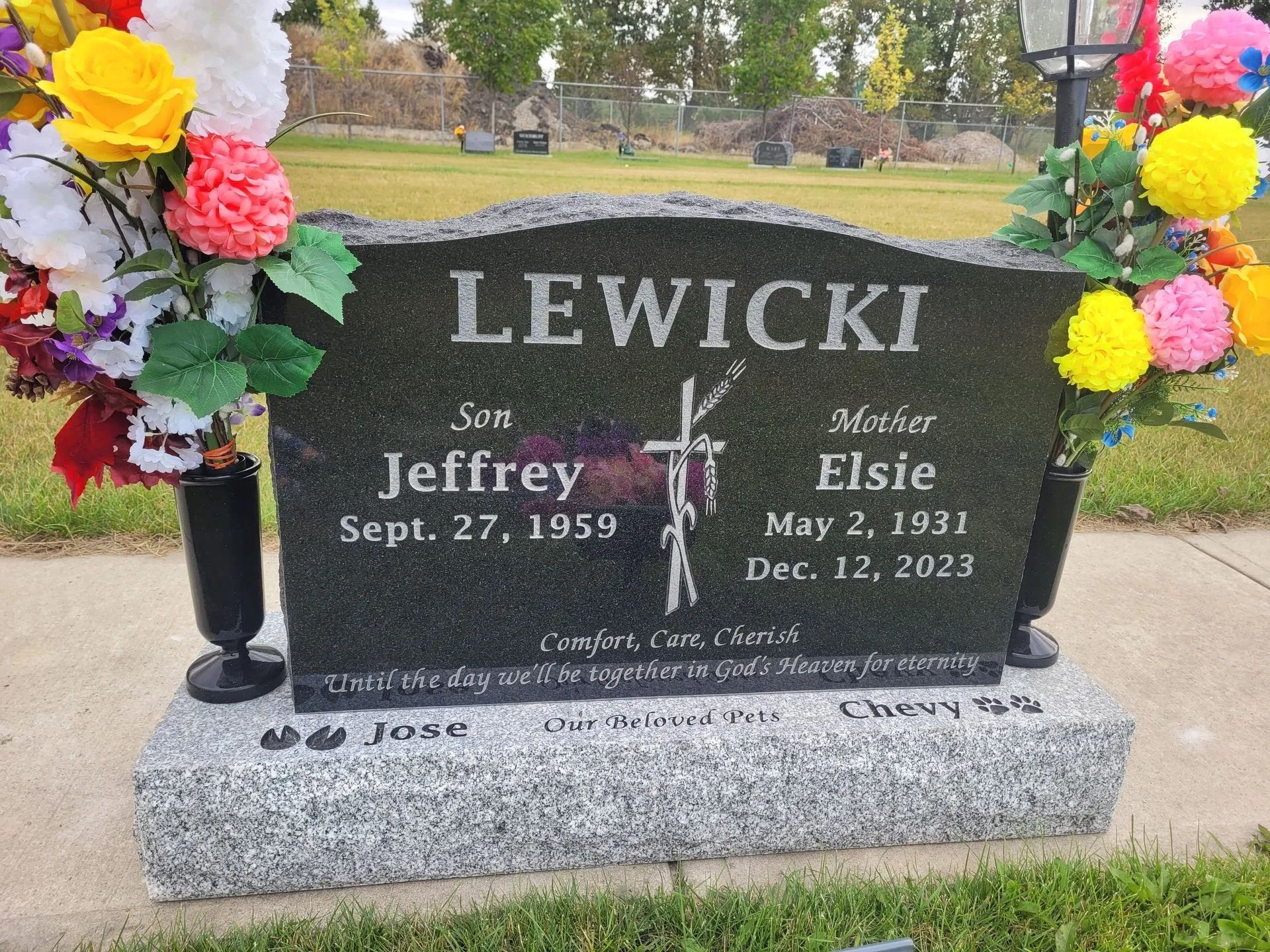 Black granite Lewicki gravestone with flowers and two names, Jeffrey and Elsie, in a cemetery.