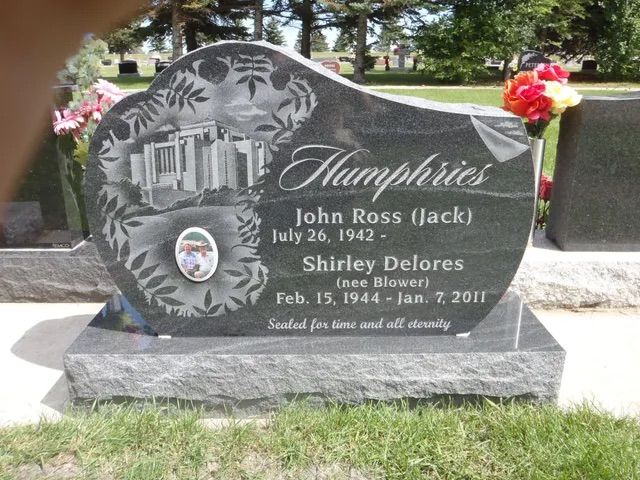 Black granite headstone with engraved hummingbird and flowers, marking John Ross Hack and Shirley Delevore in a cemetery