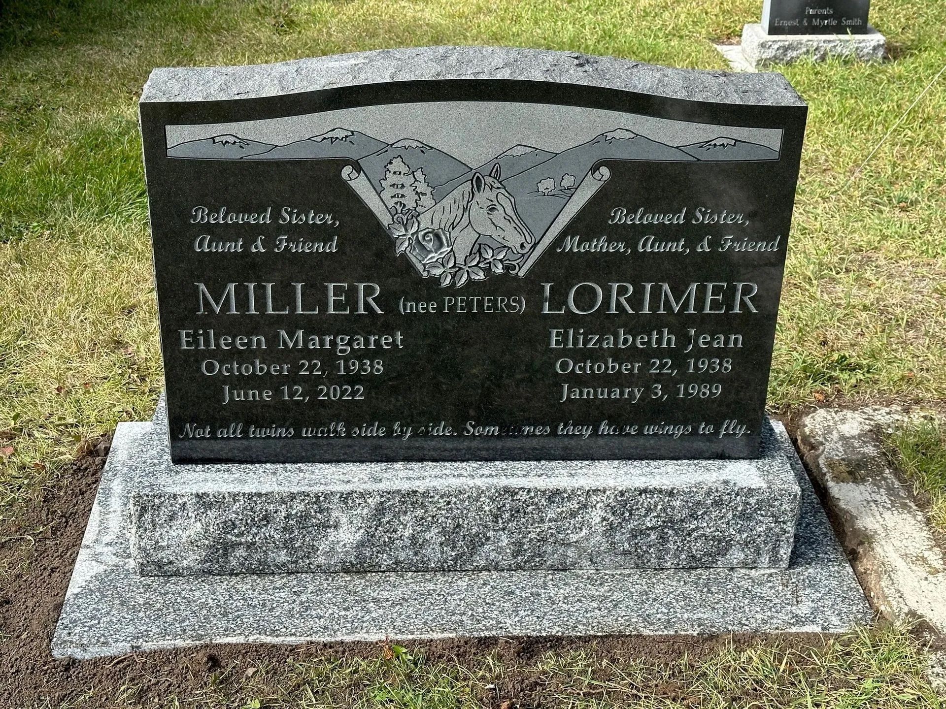 Gravestone for Miller and Lorimer in a grassy cemetery, with engraved text and a butterfly design.
