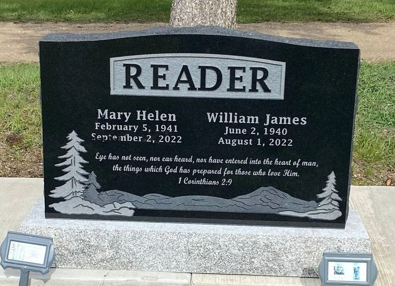 Black granite memorial headstone for the Reader family with engraved names and a tree motif in a cemetery.