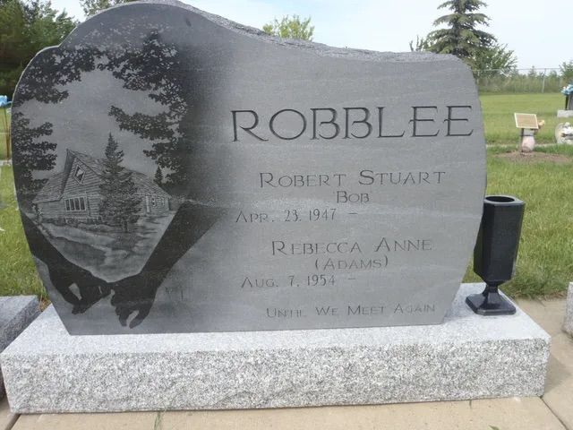 Gravestone marked “ROBBLEE” with engraved portraits and names in a cemetery