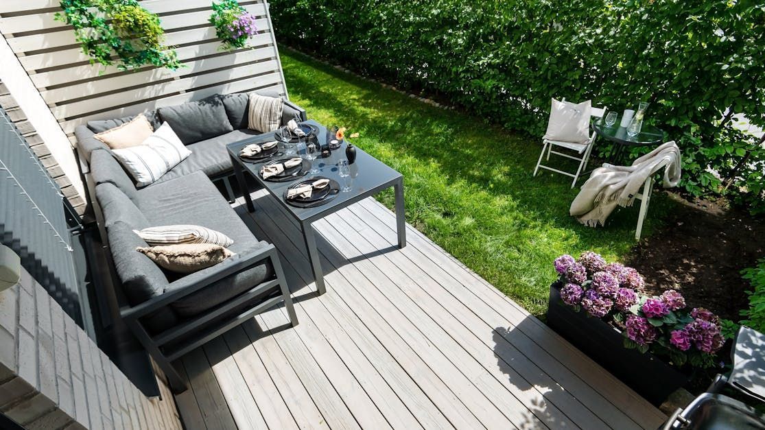 A beautiful deck with furniture, plants, and green lawn