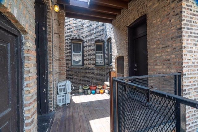 A hallway between two brick buildings with a metal fence.