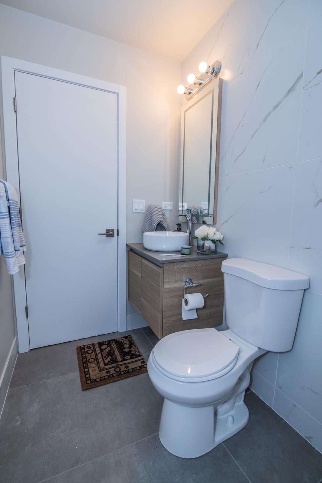 A bathroom with a toilet , sink and mirror.