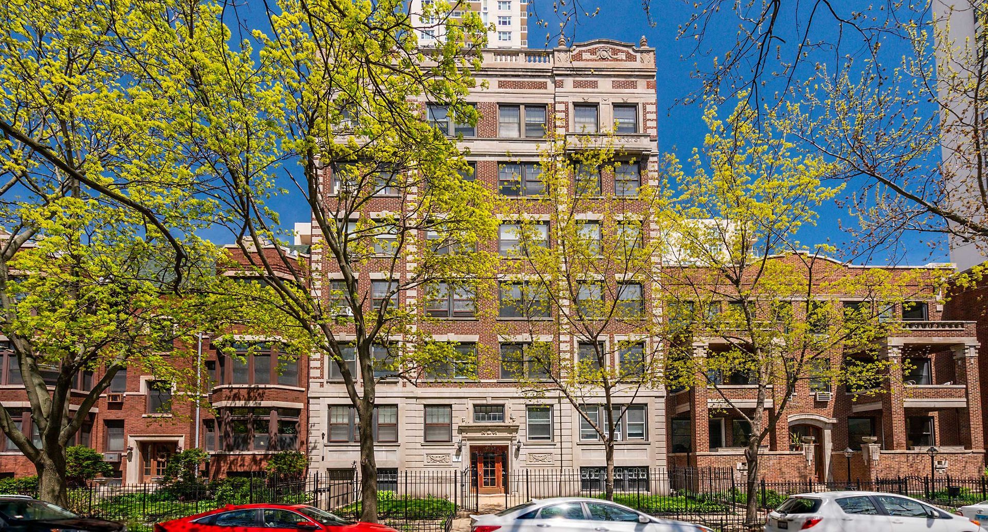A large apartment building with a lot of cars parked in front of it.