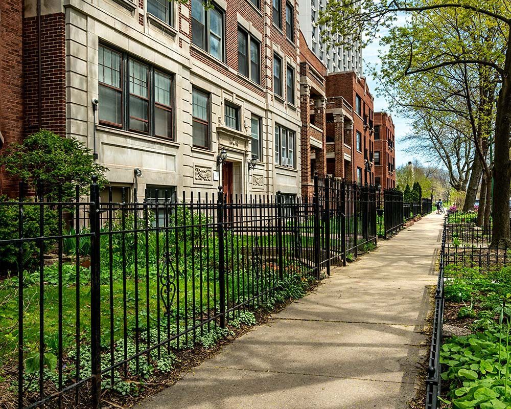 A sidewalk leading to a building with a wrought iron fence