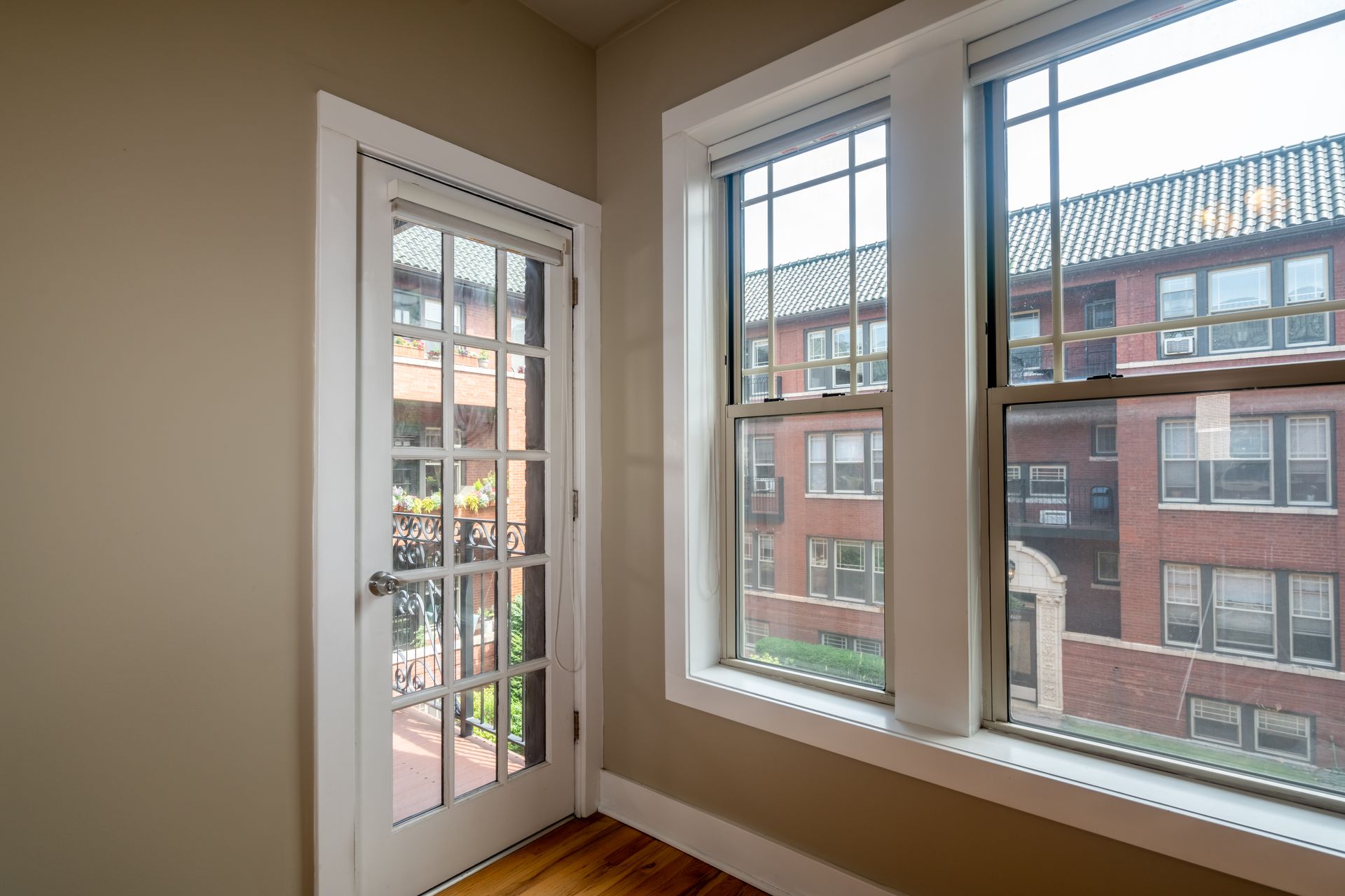 An empty room with two windows and a door leading to a balcony.