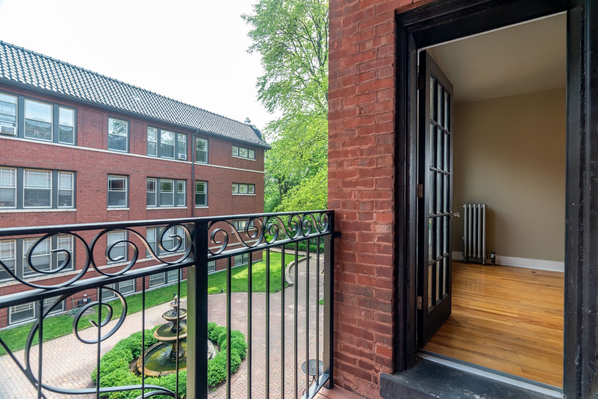 A balcony with a wrought iron railing and a brick building in the background.