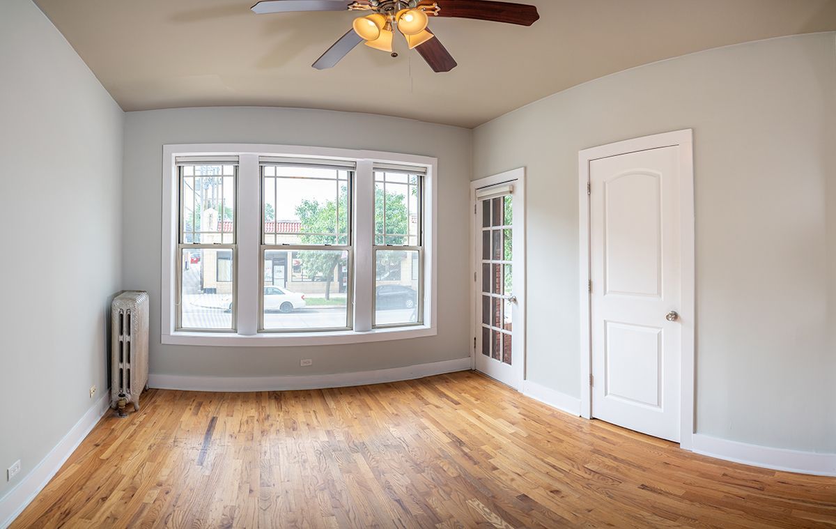An empty room with hardwood floors and a ceiling fan