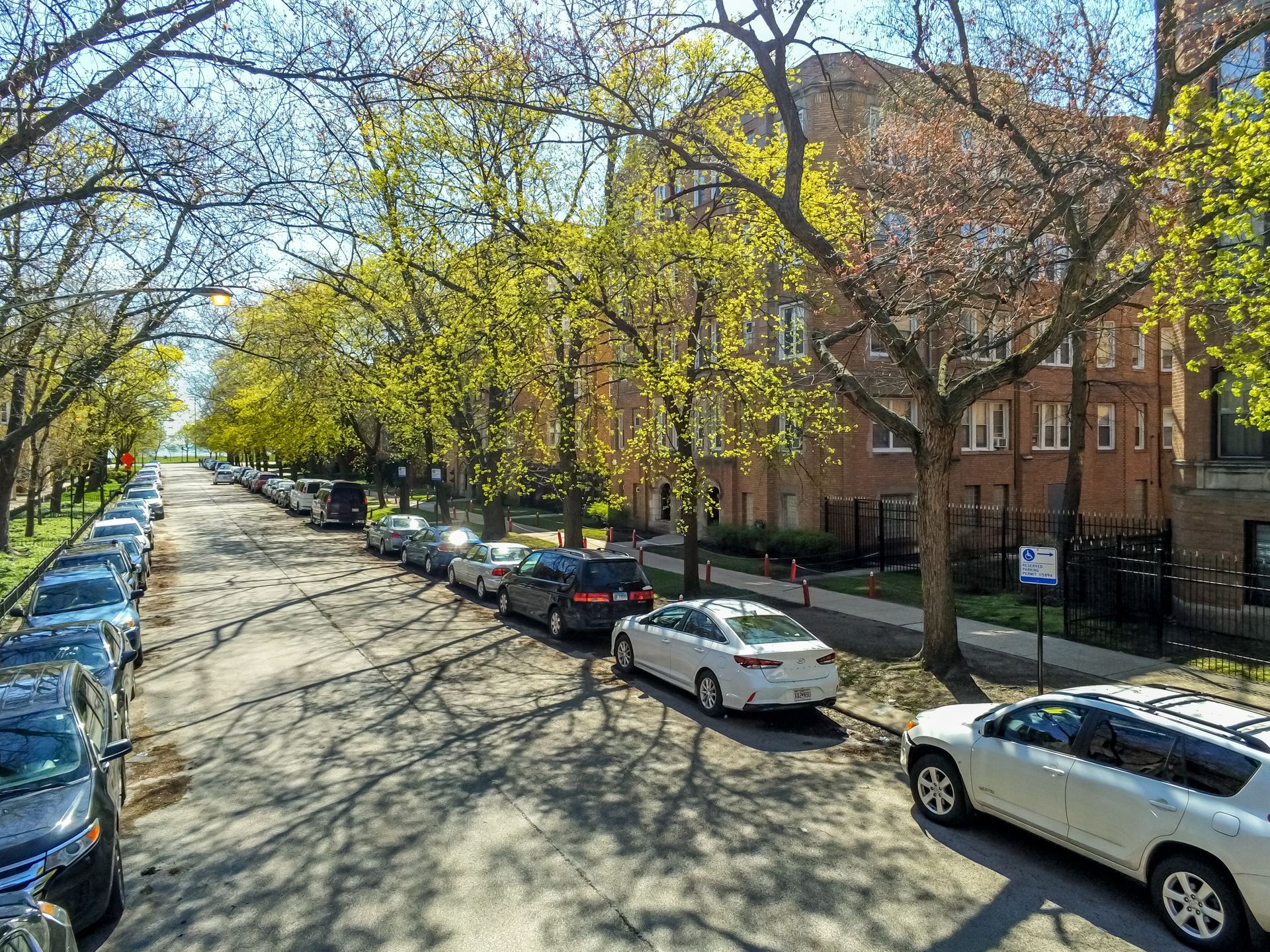 A row of cars are parked on the side of a street.