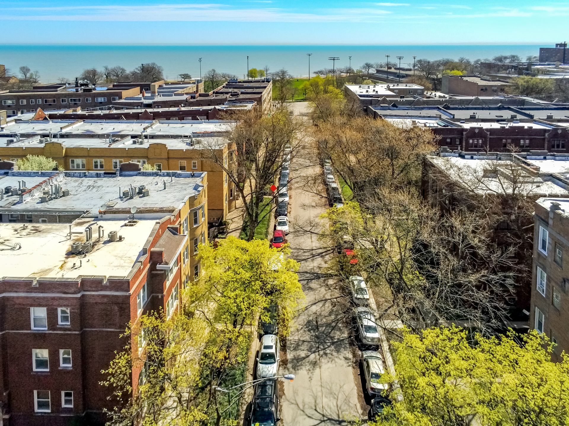 An aerial view of a city street with cars parked on the side of it.
