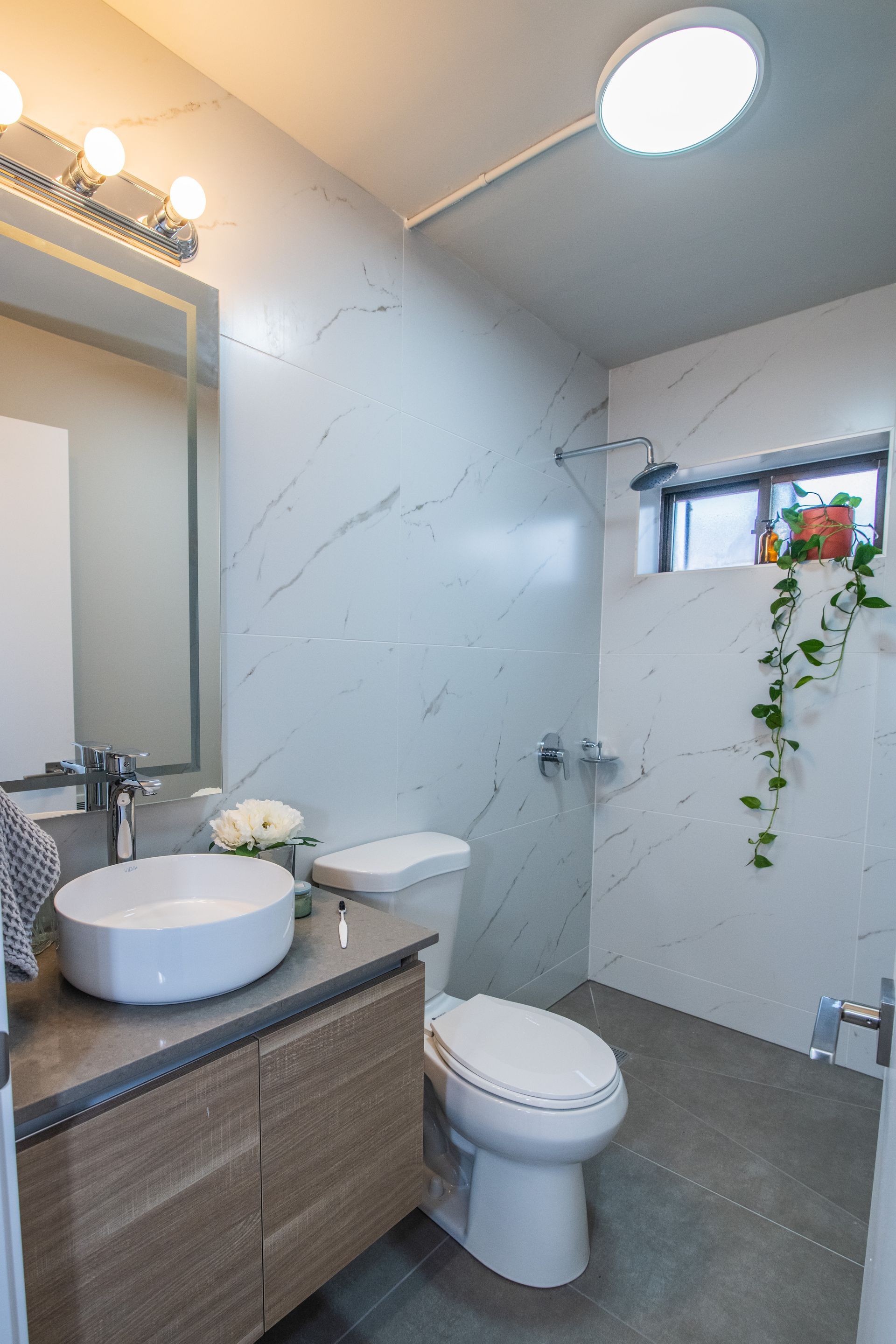 A bathroom with a toilet , sink and mirror.