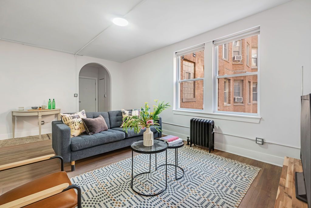 A living room with a couch , two coffee tables , and a rug.